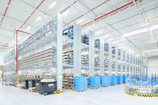 Almacén con estantes altos y contenedores azules