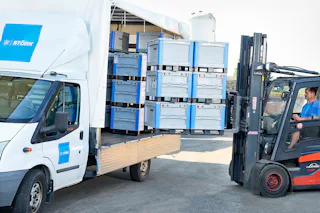 grote kunststofbakken in closed loop systeem worden geladen in vrachtwagen