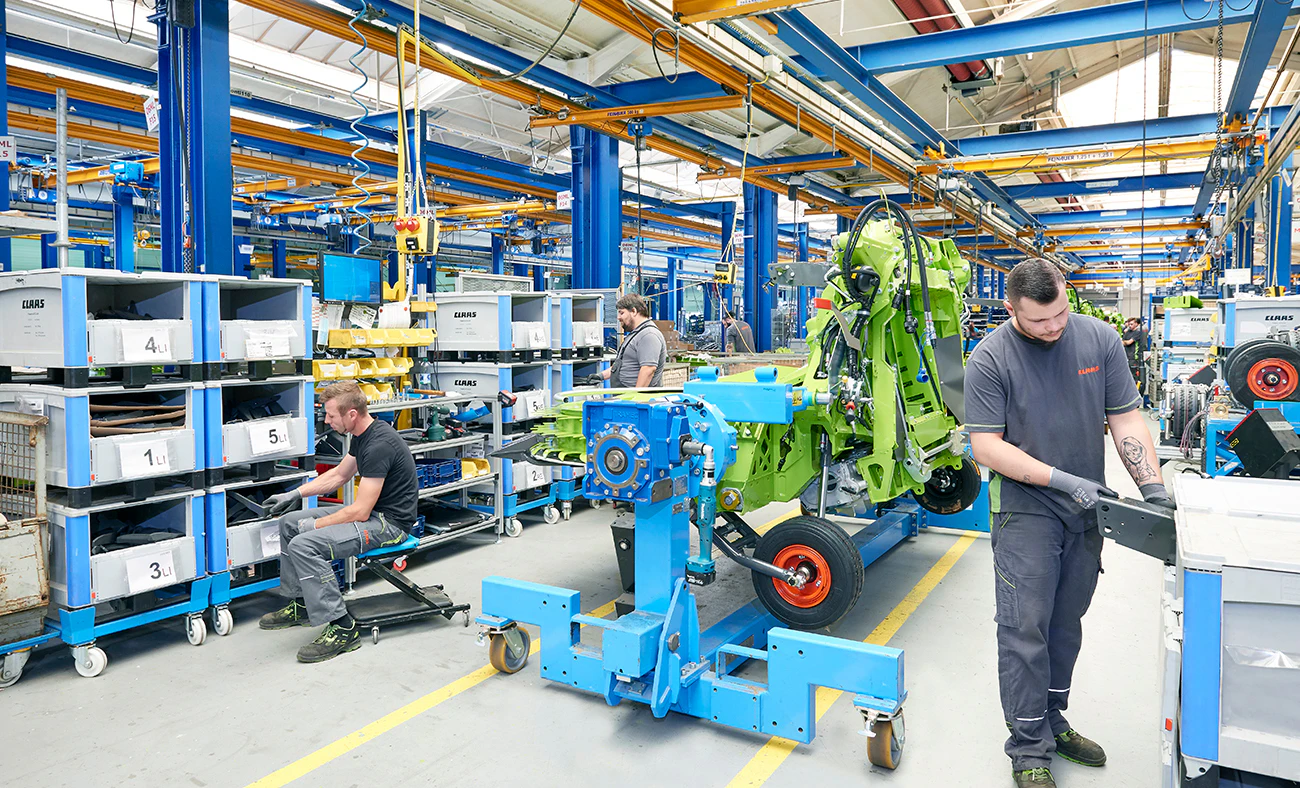 Assemblagelijn met grote kunststofbakken die onderdelen aanvoeren.