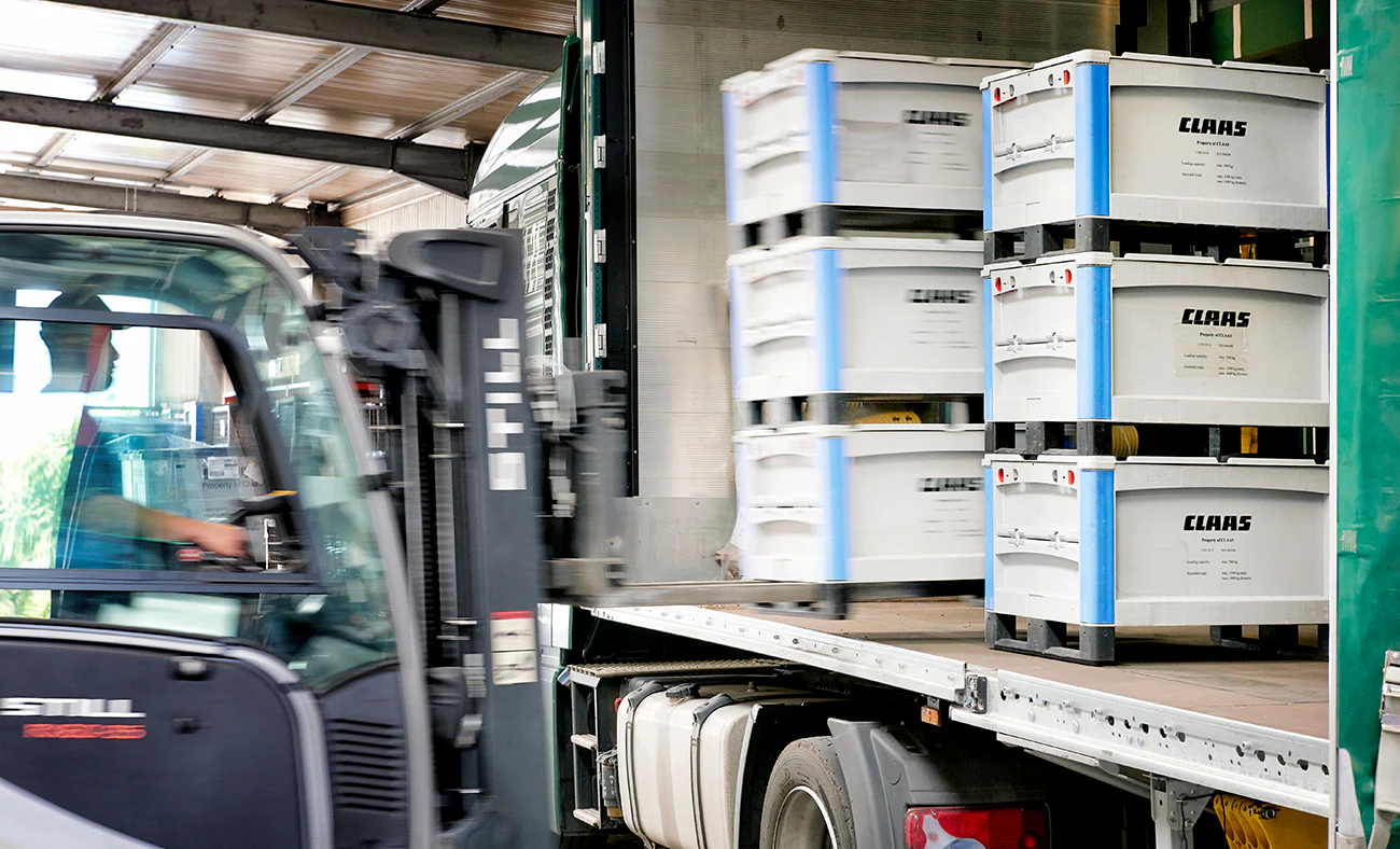 Grote kunststofbakken met onderdelen worden in vrachtwagen geladen voor loop