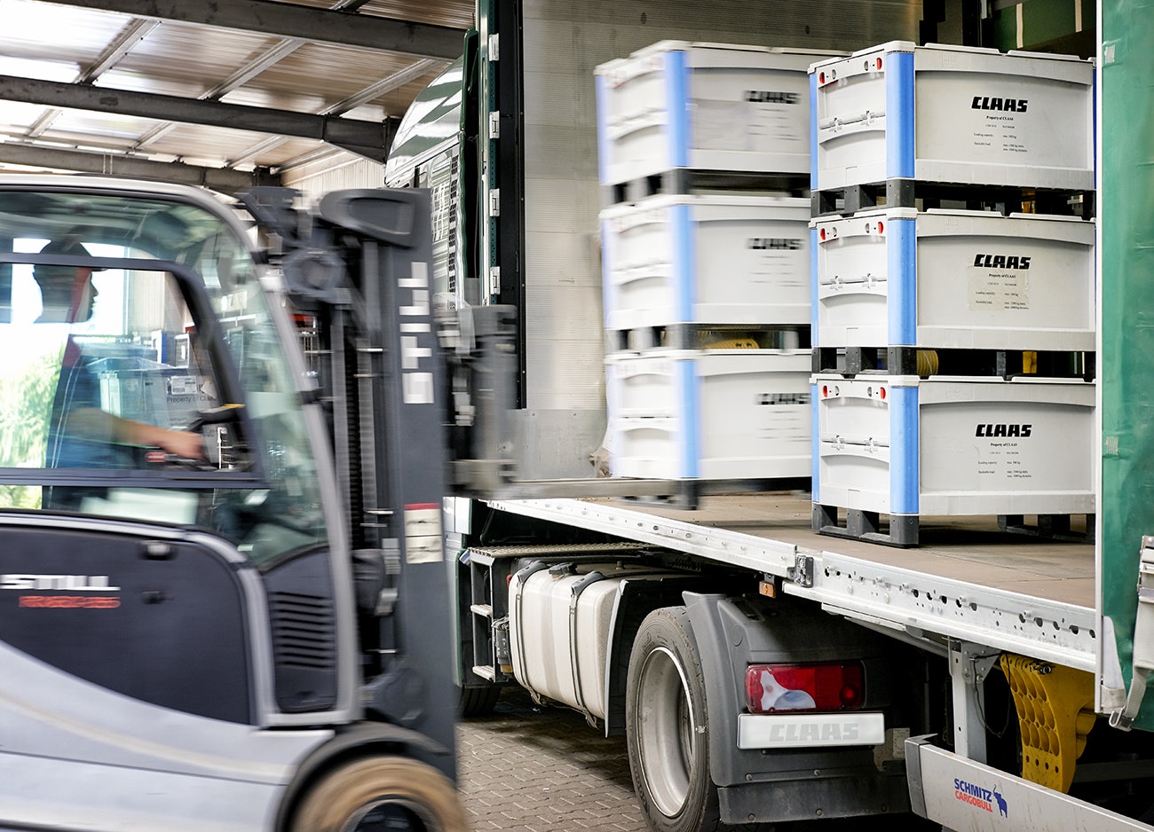 Ein Mann, der mit Hilfe eines Flurförderzeuges, BITO Schwerlastbehälter SL in einen LKW stellt.