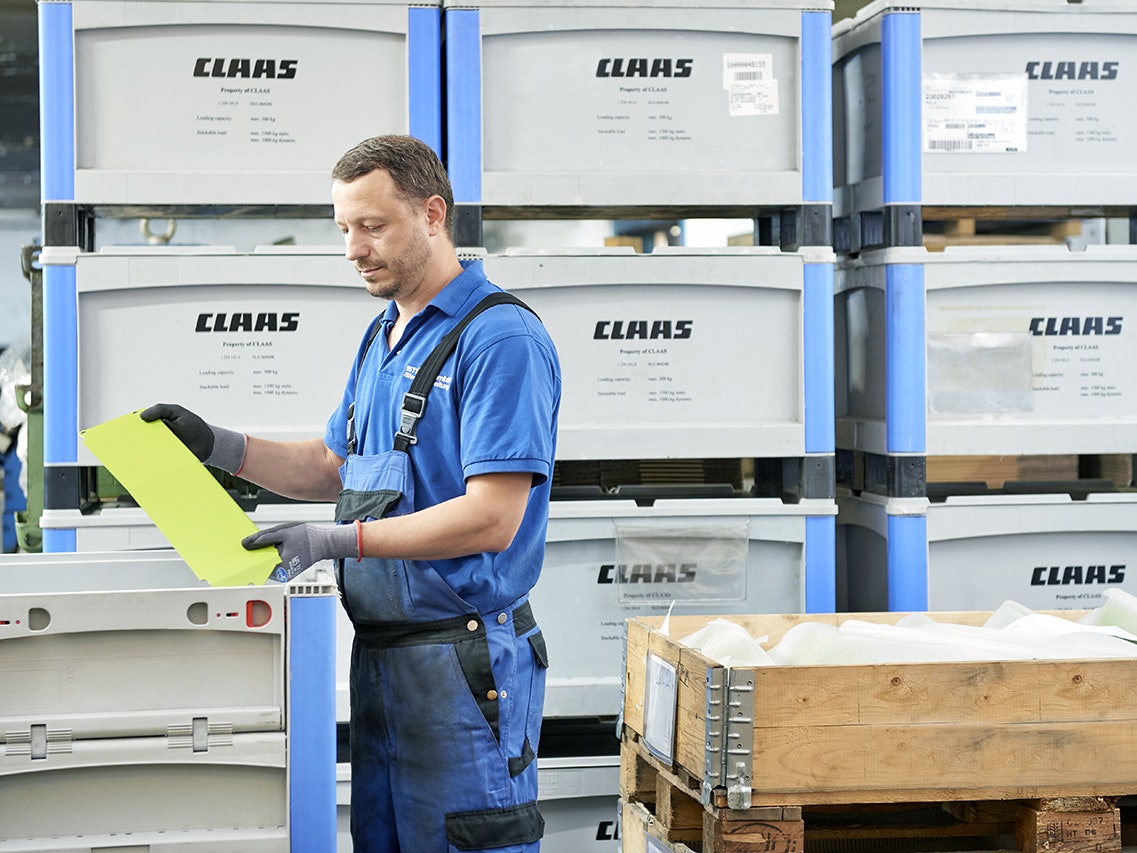 Ein Mann der Teile in einen BITO Schwerlastbehälter packt.