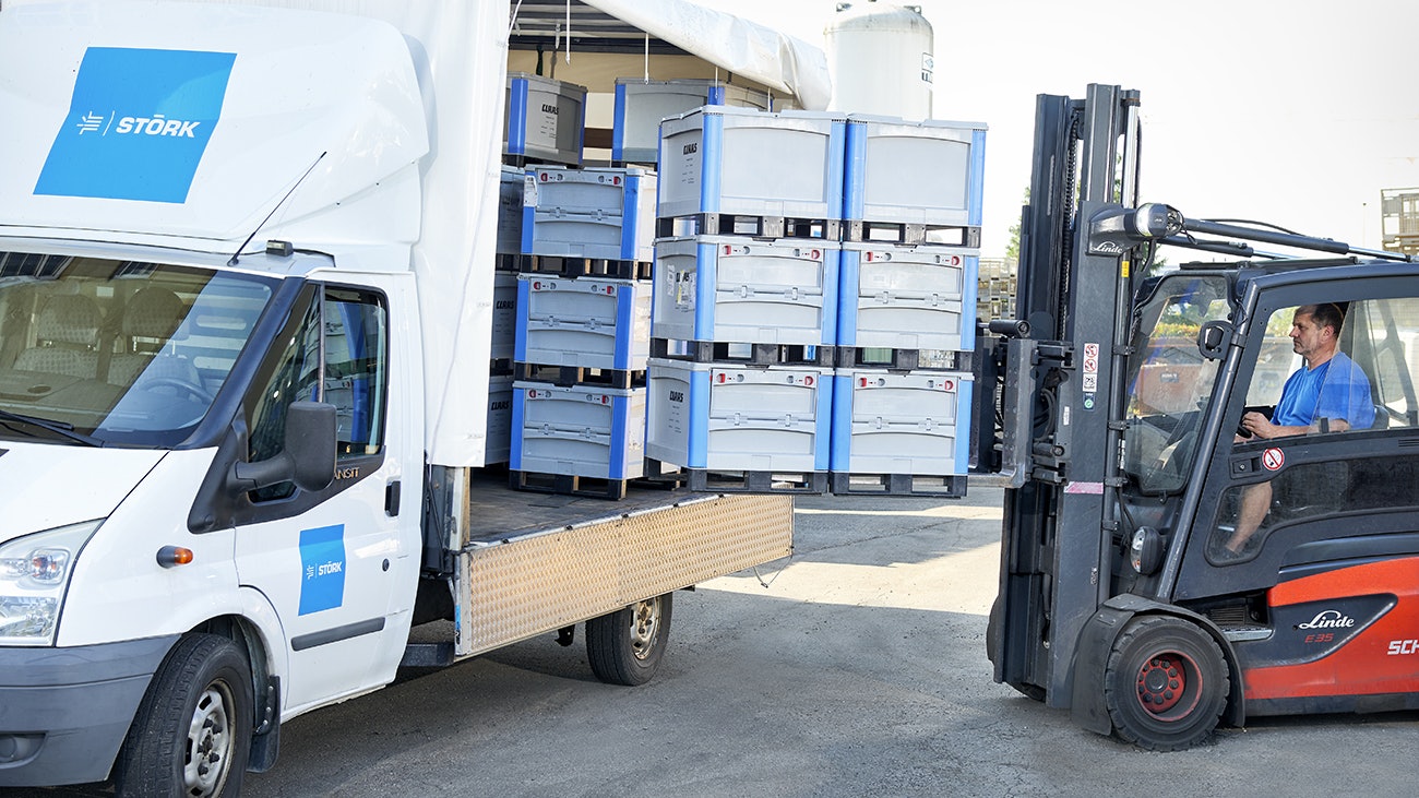 Ein Mann, der mit einem Gabelstapler, BITO Schwerlastbehälter in einen Transporter stellt.