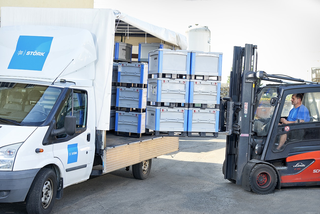Ein Mann, der mit einem Gabelstapler, BITO Schwerlastbehälter in einen Transporter stellt.