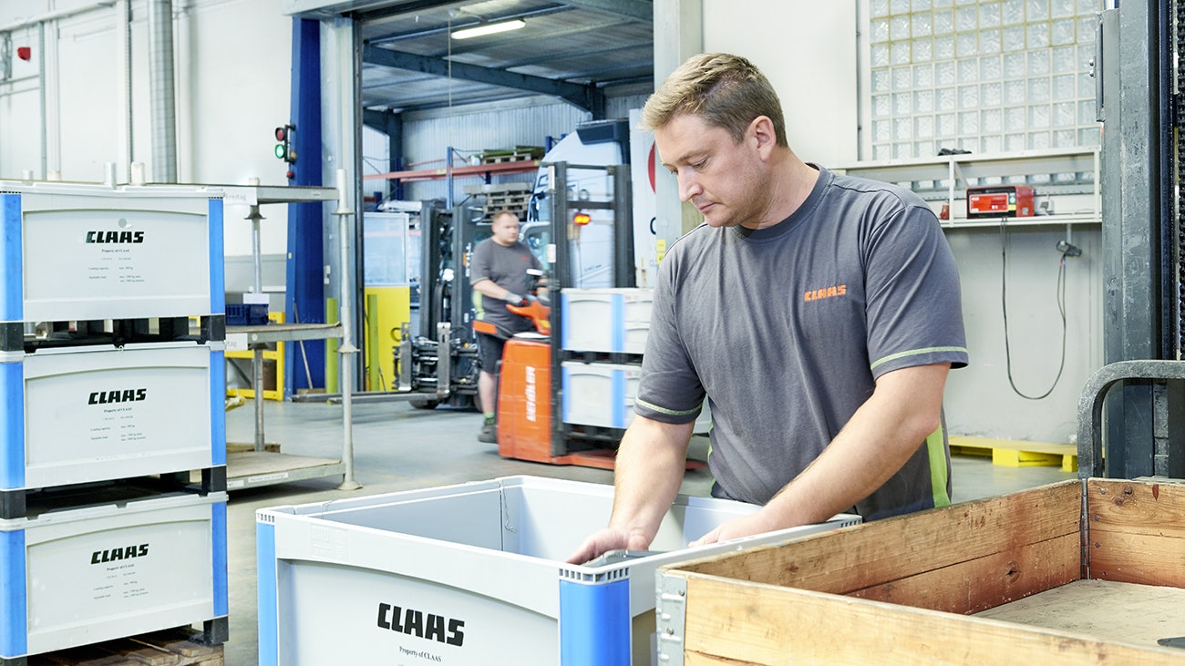 Ein Mann der Teile in einen BITO Schwerlastbehälter packt.