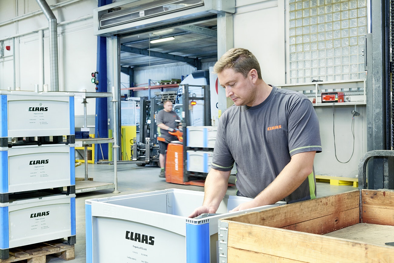 Ein Mann der Teile in einen BITO Schwerlastbehälter packt.