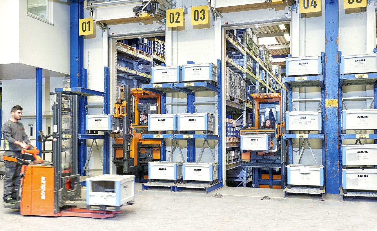 Zwei Mitarbeiter die, mit Flurförderzeugen, BITO Schwerlastbehälter SL bereitstellen, während ein dritter einen der Behälter abtransportiert.