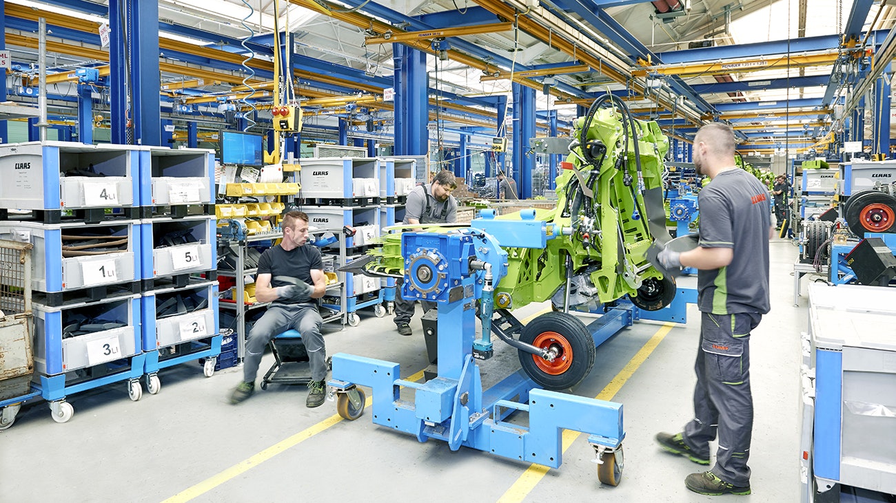 Drei Mitarbeiter bei der Montage einer Maschine für die Landwirtschaft, die benötigten Teile liegen in BITO Schwerlastbehältern.