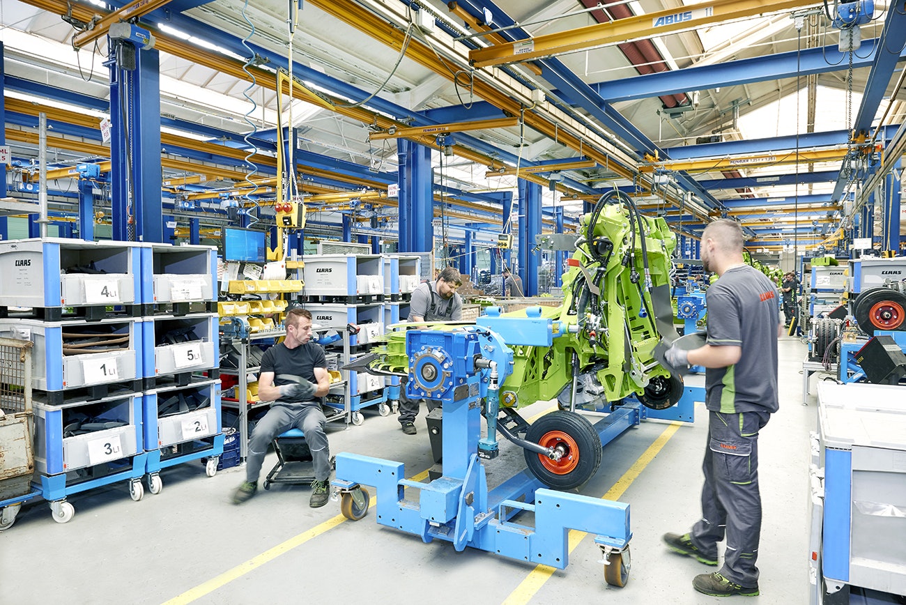 Drei Mitarbeiter bei der Montage einer Maschine für die Landwirtschaft, die benötigten Teile liegen in BITO Schwerlastbehältern.