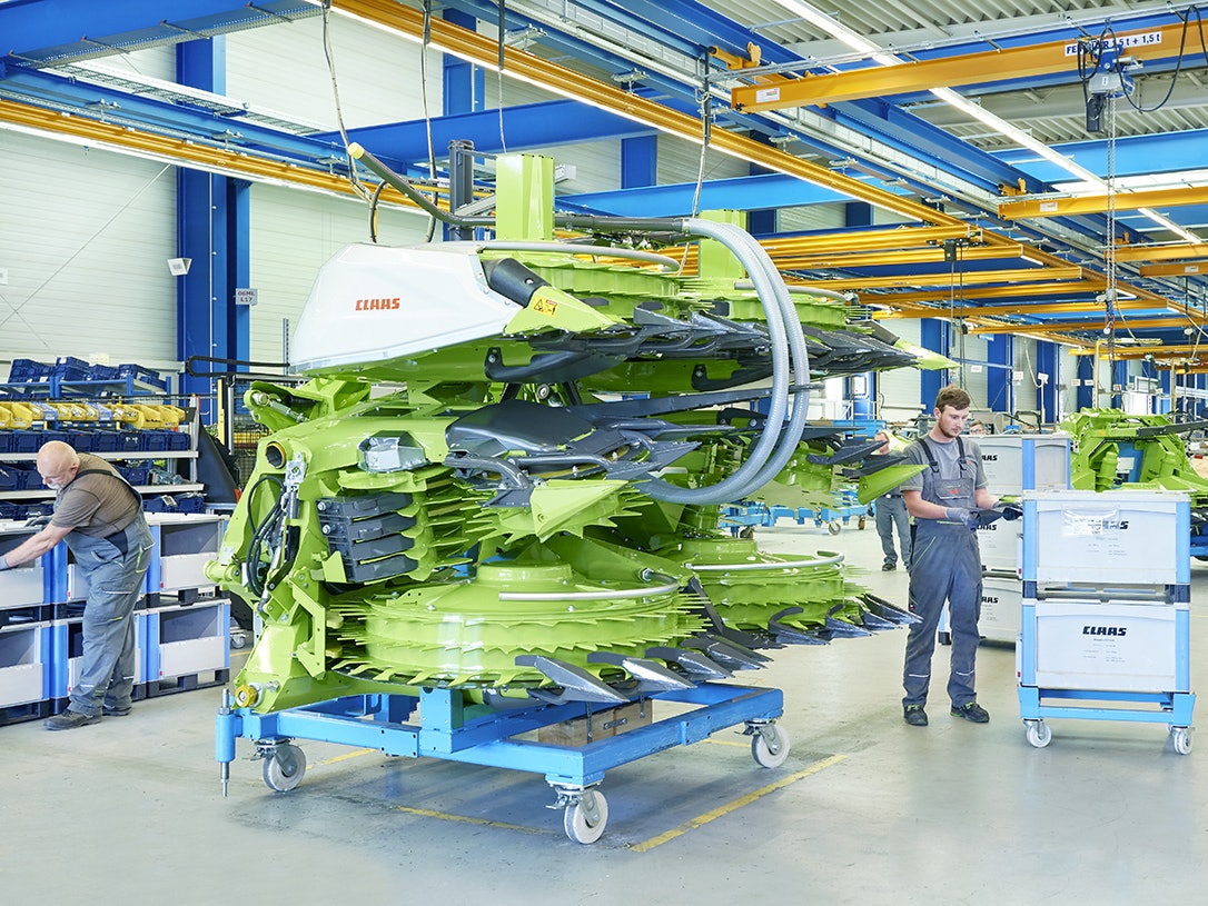 Drei Mitarbeiter bei der Montage einer Maschine für die Landwirtshaft, die benötigten Teile liegen in BITO Schwerlastbehältern.