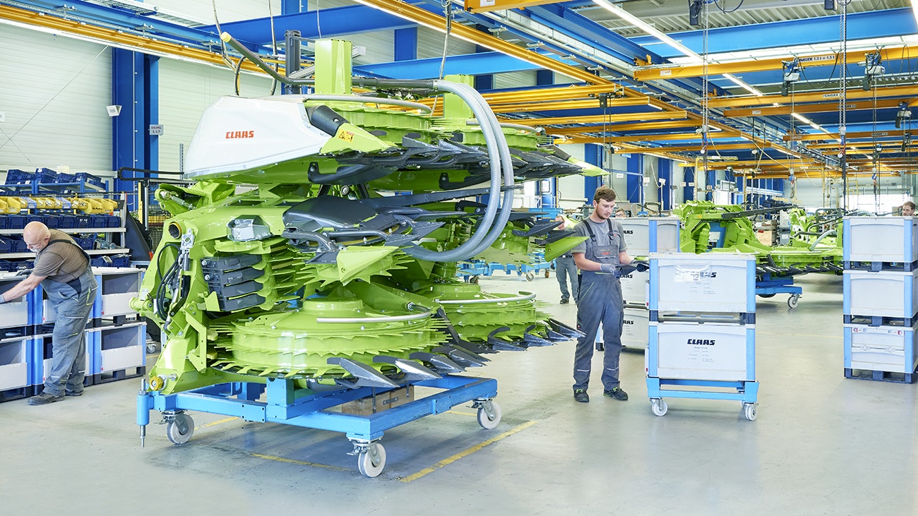 Drei Mitarbeiter bei der Montage einer Maschine für die Landwirtshaft, die benötigten Teile liegen in BITO Schwerlastbehältern.