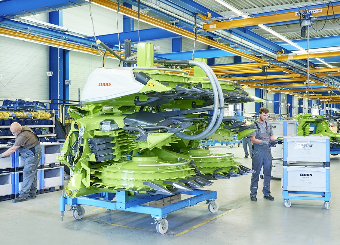 Drei Mitarbeiter bei der Montage einer Maschine für die Landwirtshaft, die benötigten Teile liegen in BITO Schwerlastbehältern.