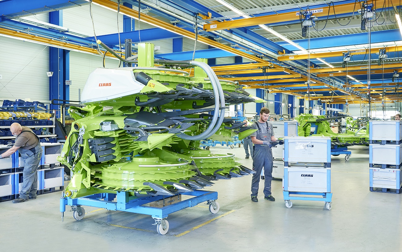 Drei Mitarbeiter bei der Montage einer Maschine für die Landwirtshaft, die benötigten Teile liegen in BITO Schwerlastbehältern.