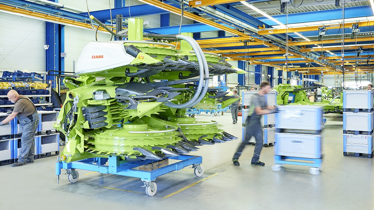 Drei Mitarbeiter bei der Montage einer Maschine für die Landwirtshaft, die benötigten Teile liegen in BITO Schwerlastbehältern.