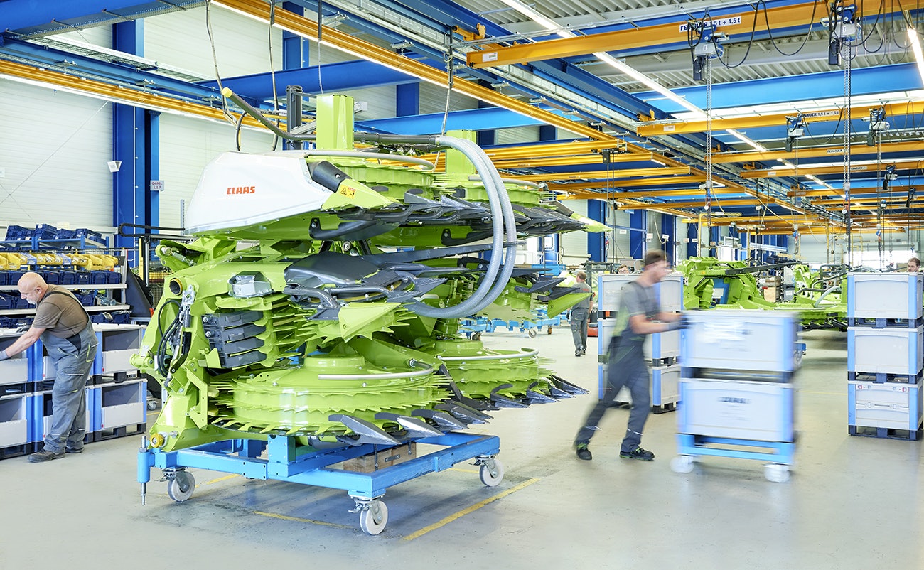 Drei Mitarbeiter bei der Montage einer Maschine für die Landwirtshaft, die benötigten Teile liegen in BITO Schwerlastbehältern.