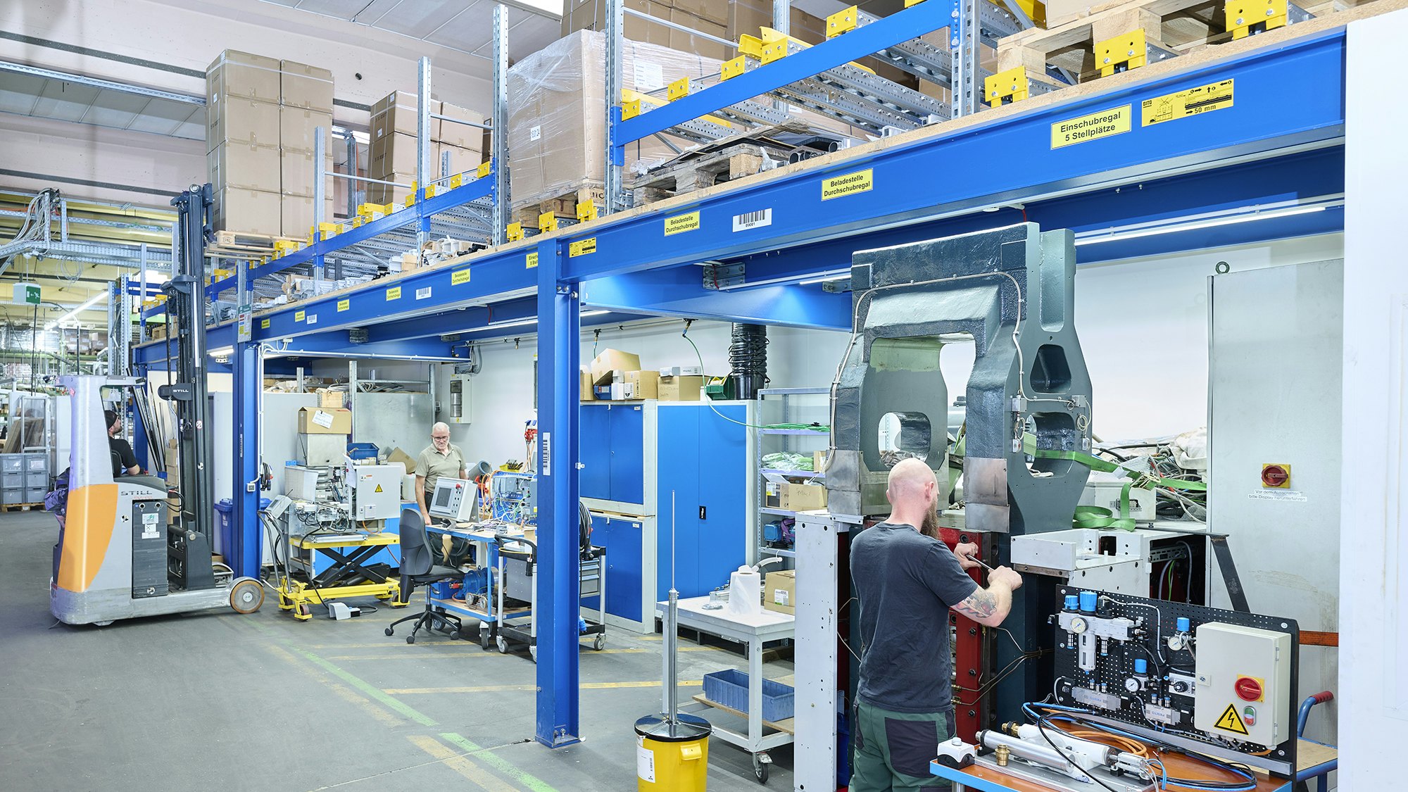 Zwei Mitarbeiter in einer Werkstatt. Über ihnen befindet sich ein Palettendurchlaufregal von BITO