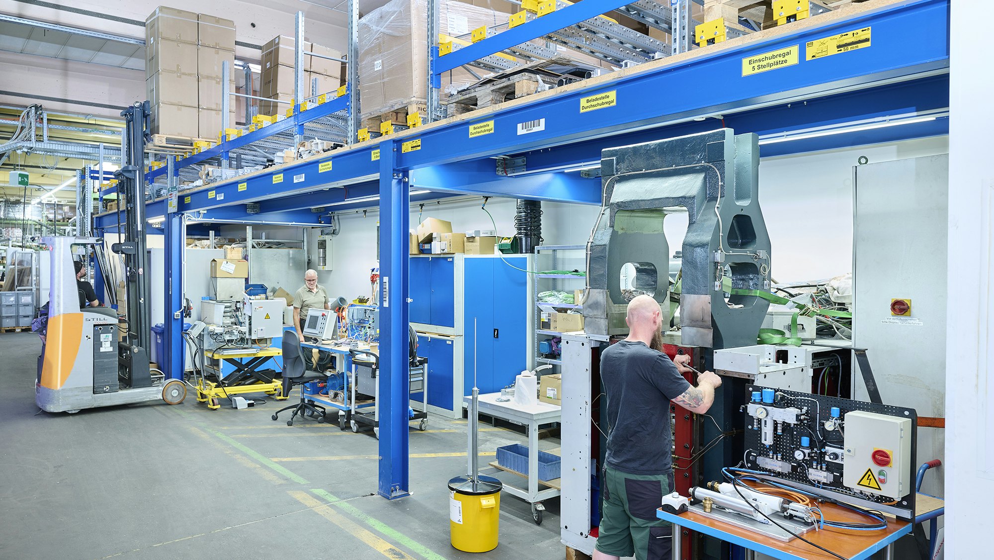Zwei Mitarbeiter in einer Werkstatt. Über ihnen befindet sich ein Palettendurchlaufregal von BITO
