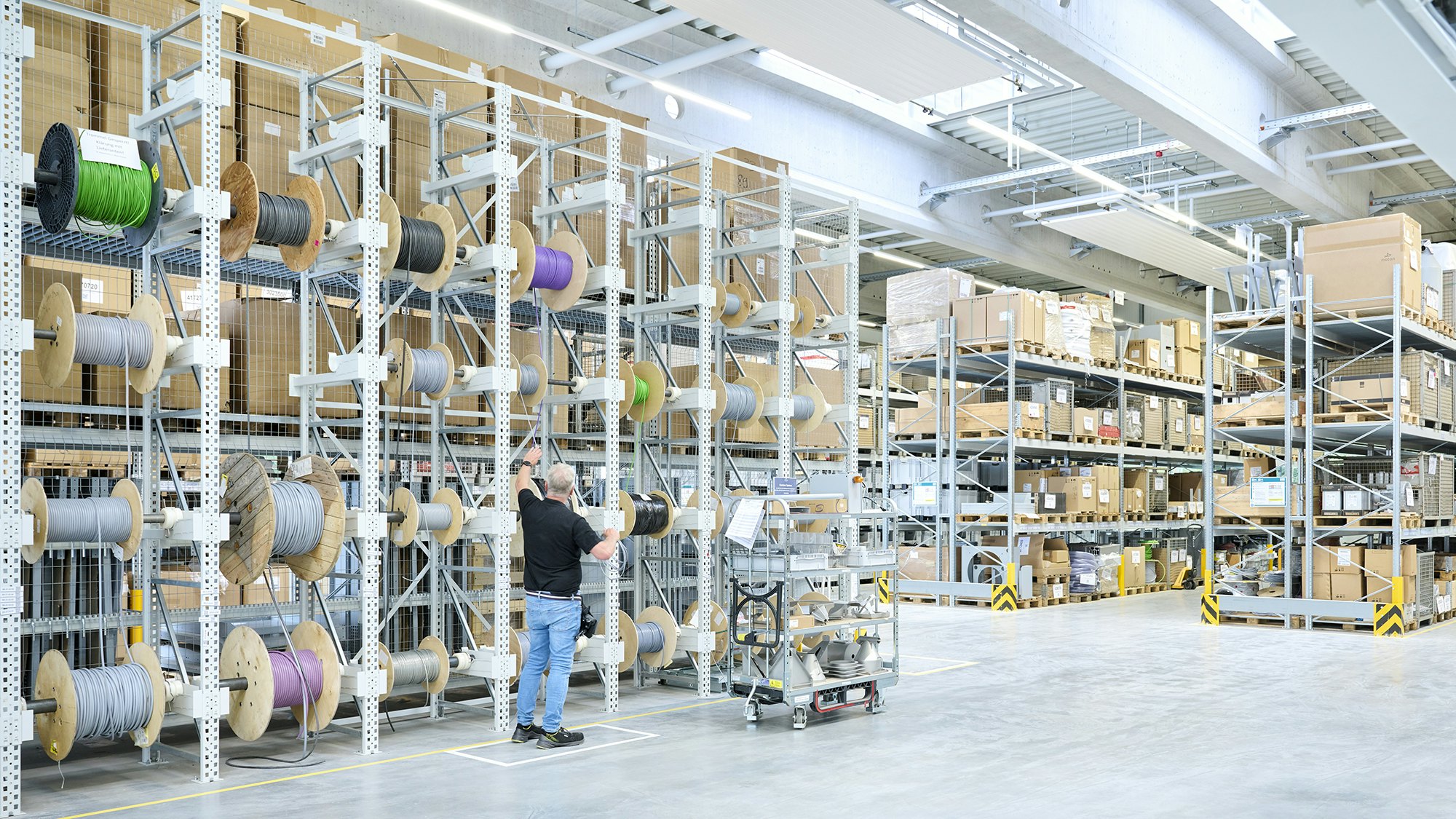 Ein Lagerarbeiter an einem Kabelrollen-Regal
