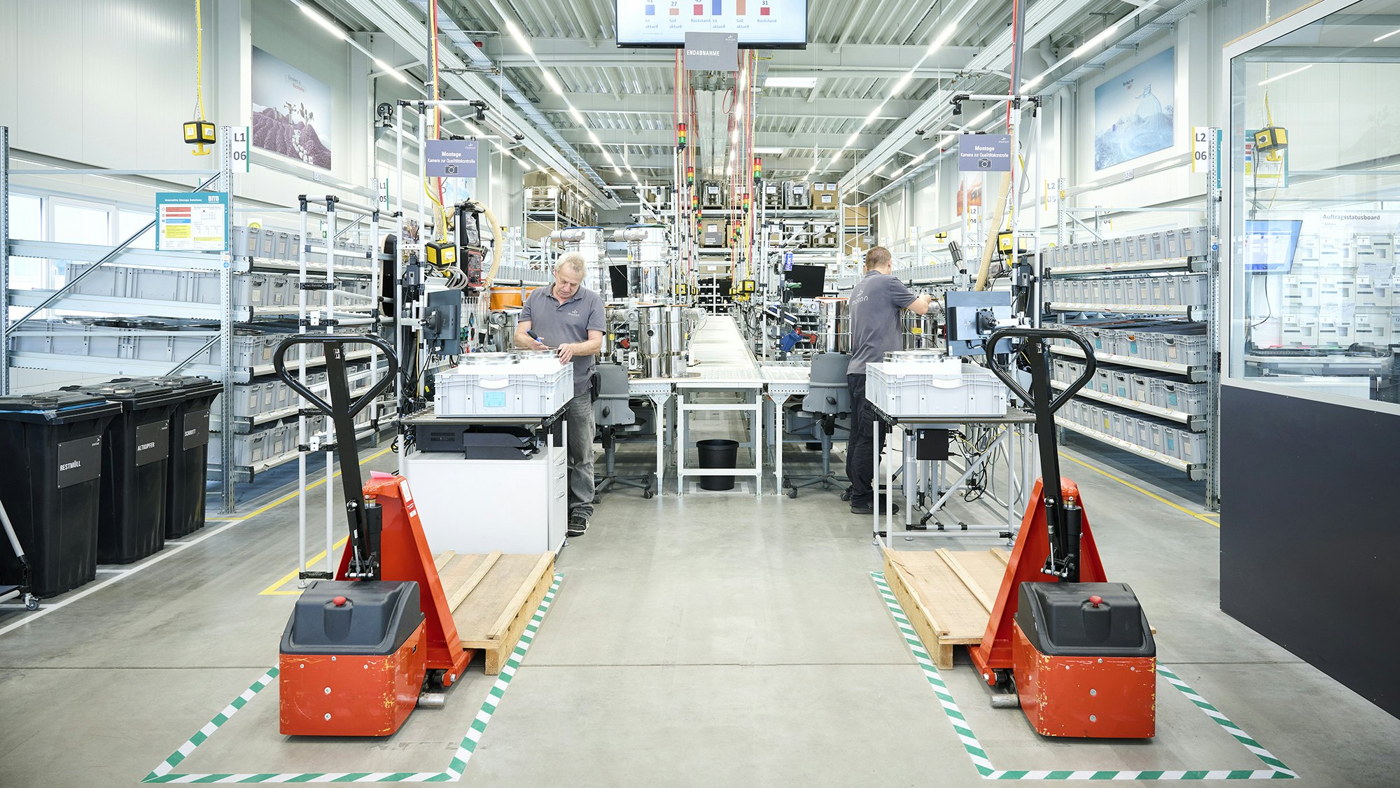 Zwei Arbeiter an einem Arbeitsplatz zwischen BITO Regalen