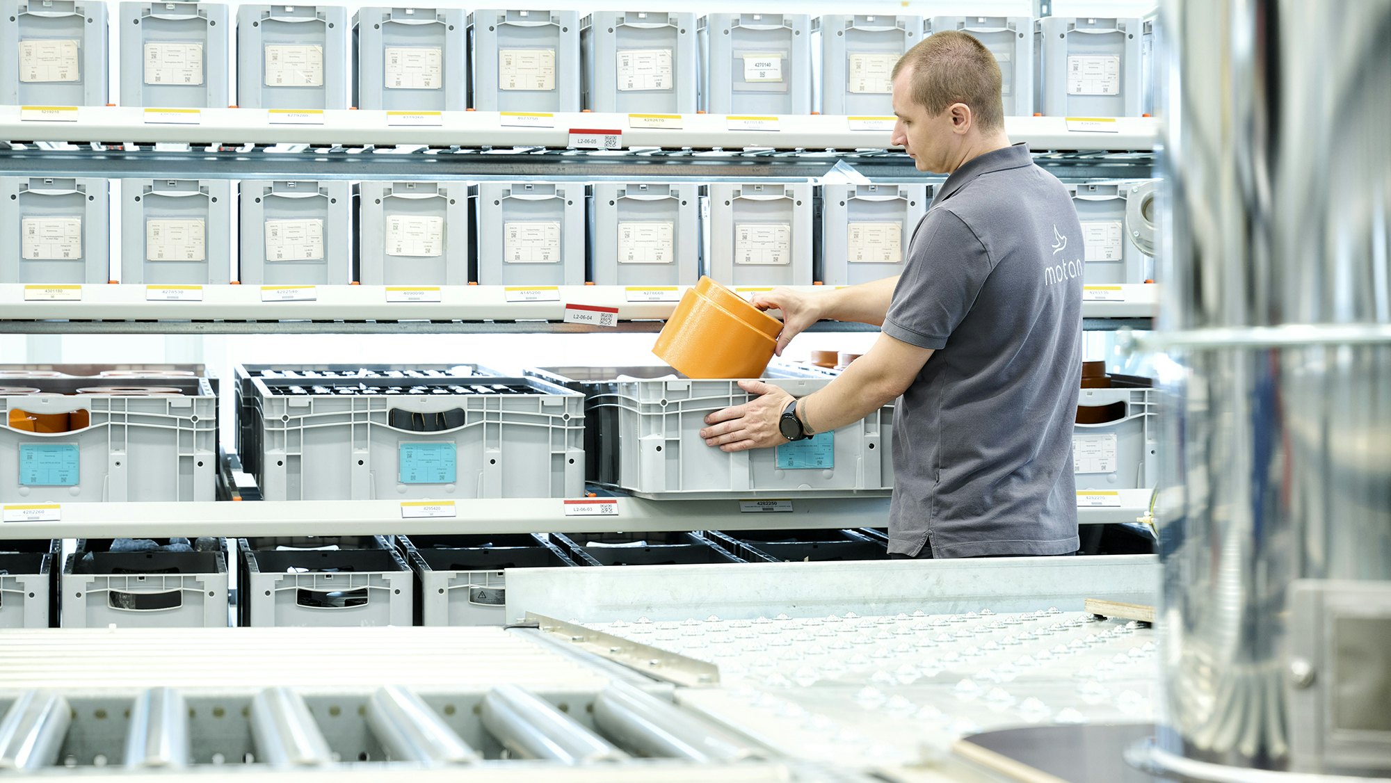 Ein Lagerarbeiter an einem BITO Durchlaufregal mit BITO Stapelbehälter