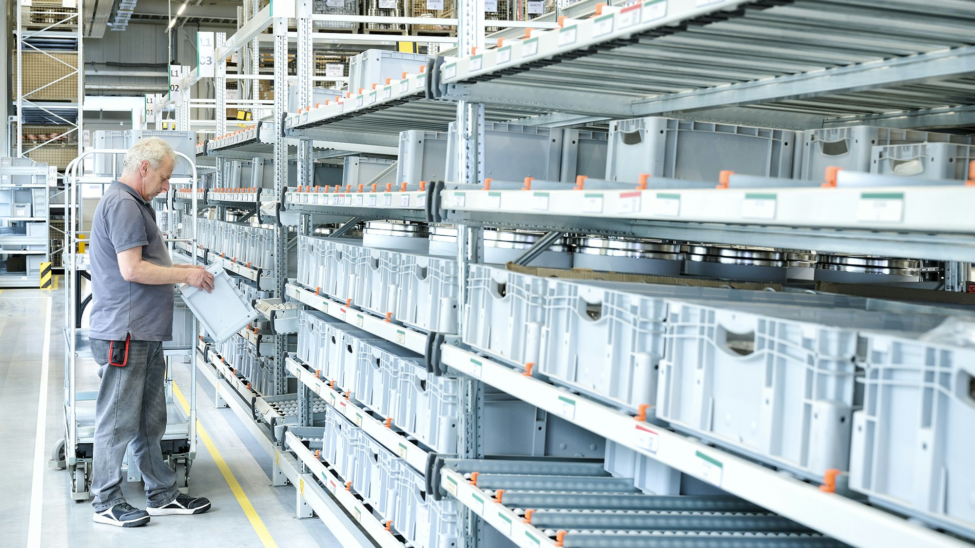 Ein Lagerarbeiter an einem BITO Durchlaufregal mit BITO Stapelbehälter