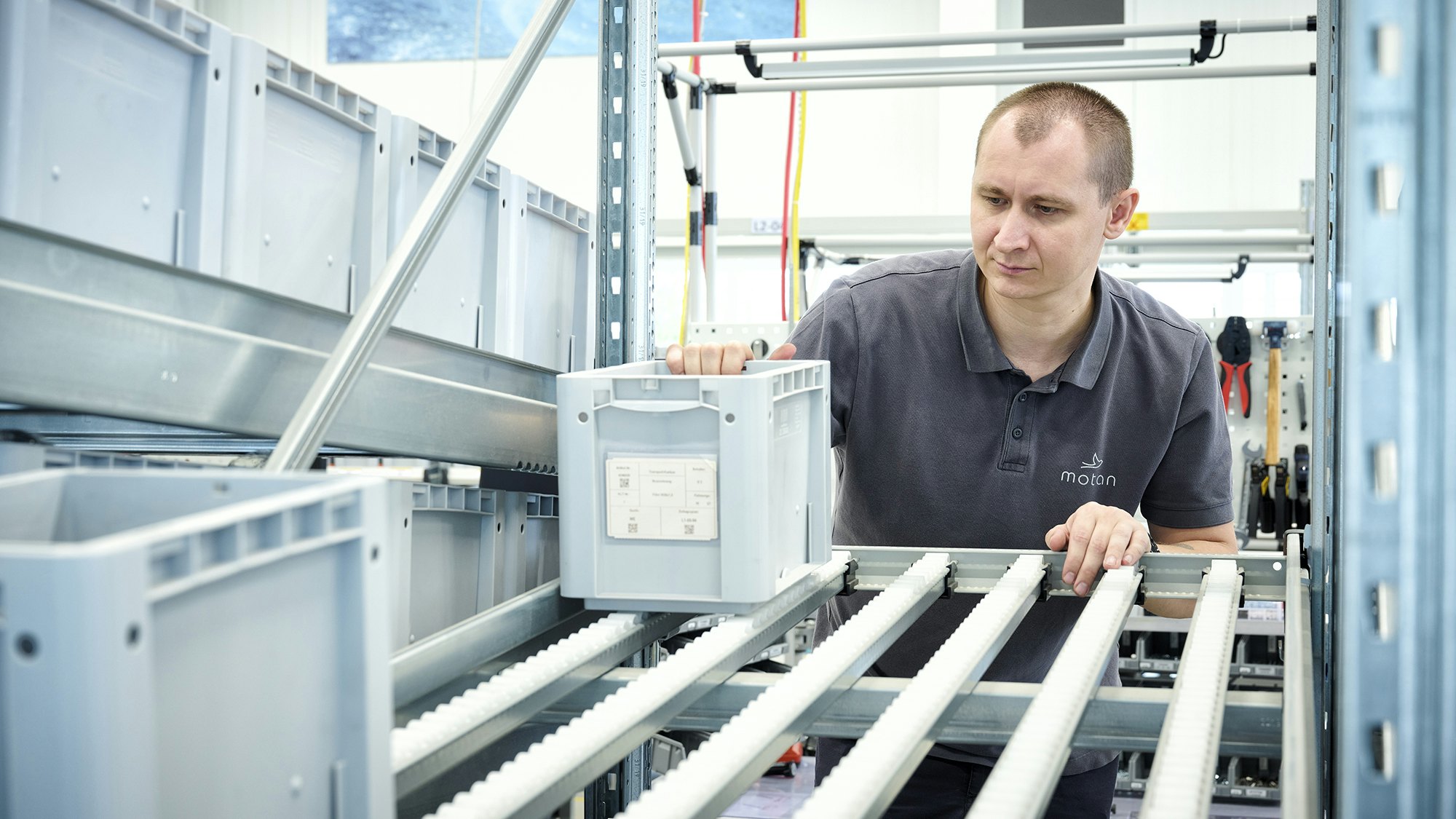 Ein Lagerarbeiter an einem BITO Durchlaufregal mit BITO Stapelbehälter