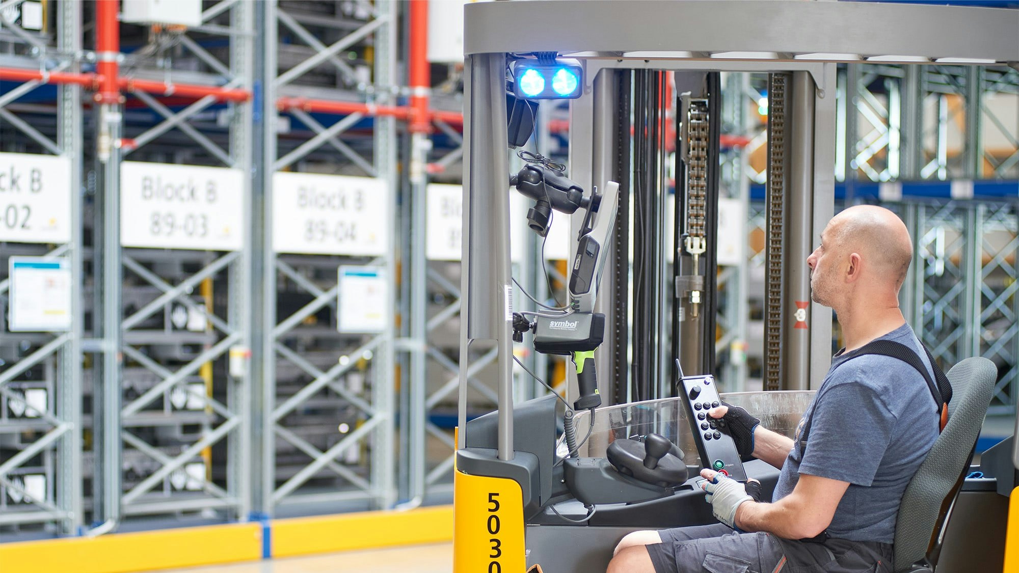 Ein Lagerarbeiter in einem Flurförderzeug vor Verfahrbaren BITO Palettenregalen