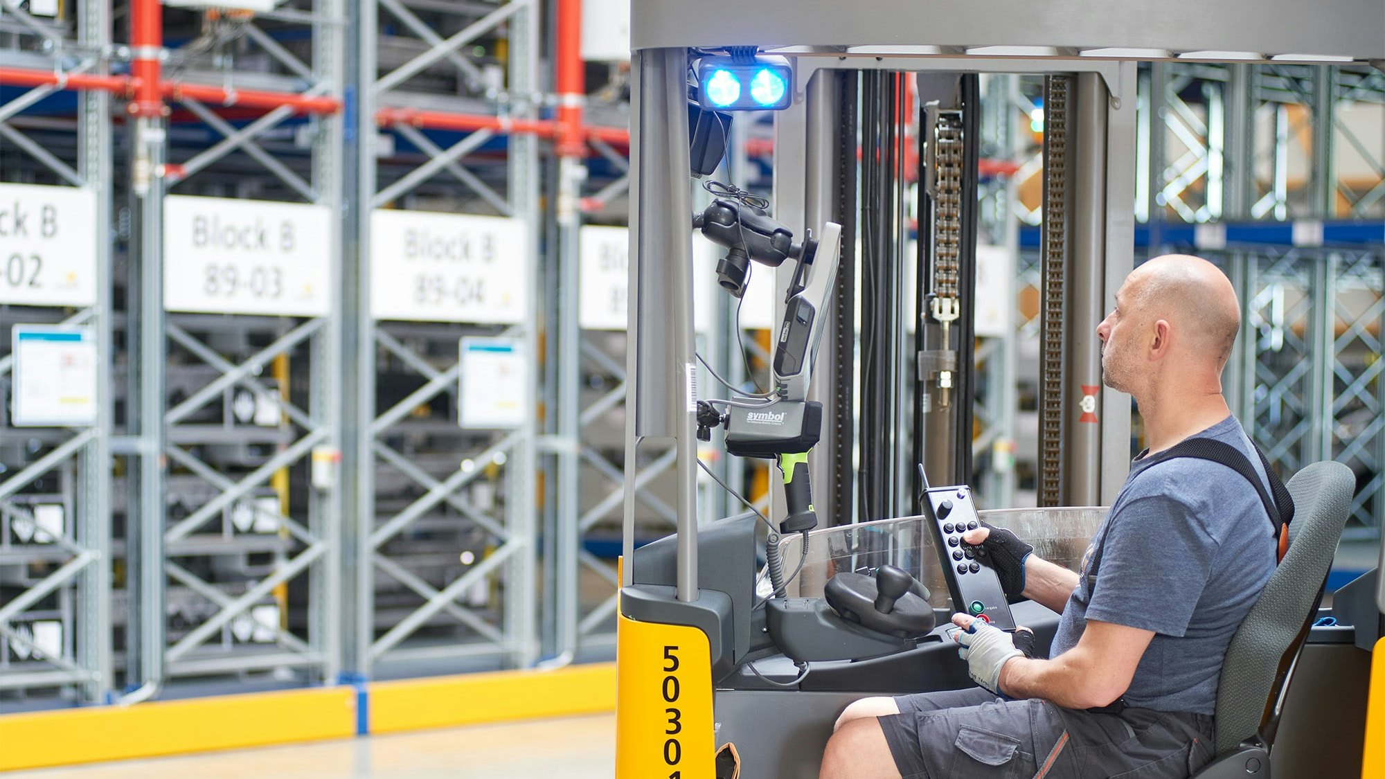 Ein Lagerarbeiter in einem Flurförderzeug vor Verfahrbaren BITO Palettenregalen