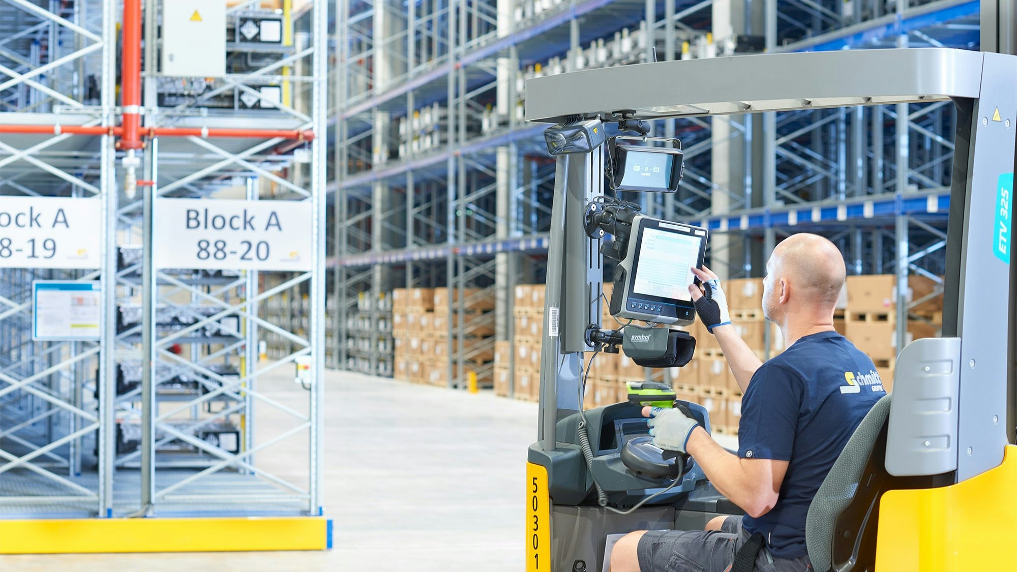 Ein Lagerarbeiter in einem Flurförderzeug vor Verfahrbaren BITO Palettenregalen