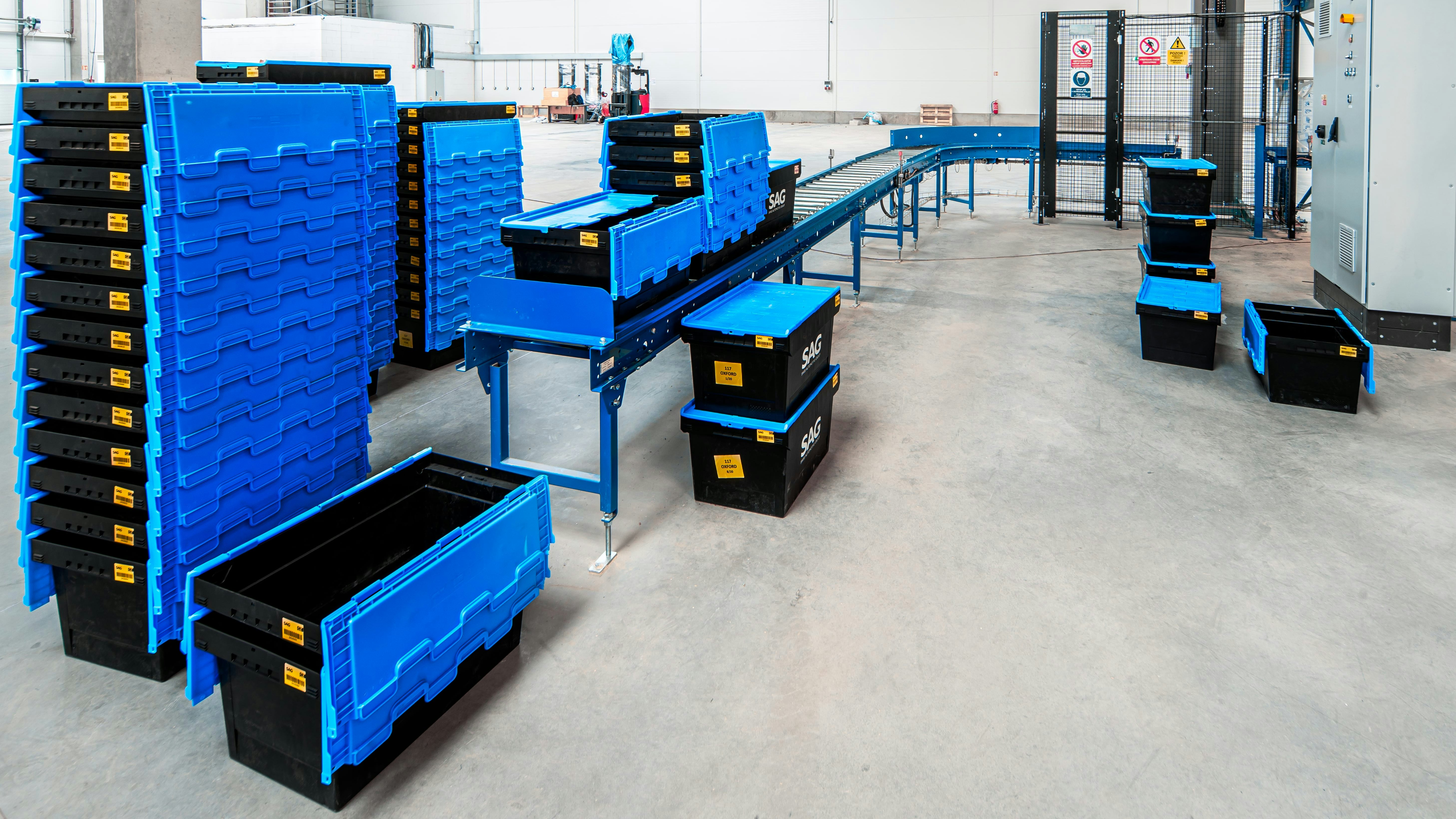 BITO Mehrwegbehälter, gestapelt und auf einer Fördertechnik.