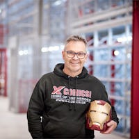 Ein Mann mit Iron Man-Helm in der Hand vor einem BITO Regal