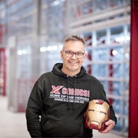 Ein Mann mit Iron Man-Helm in der Hand vor einem BITO Regal