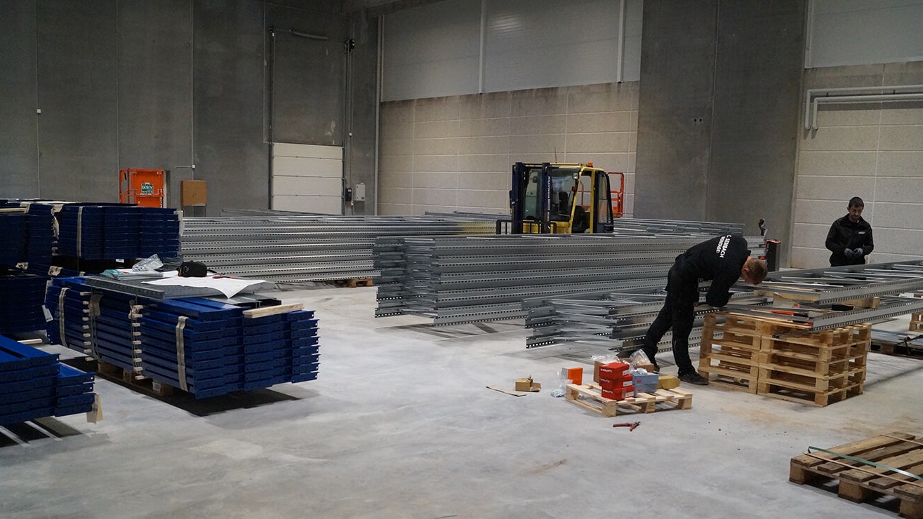 Drei Monteure beim Aufbau von Palettenregalen