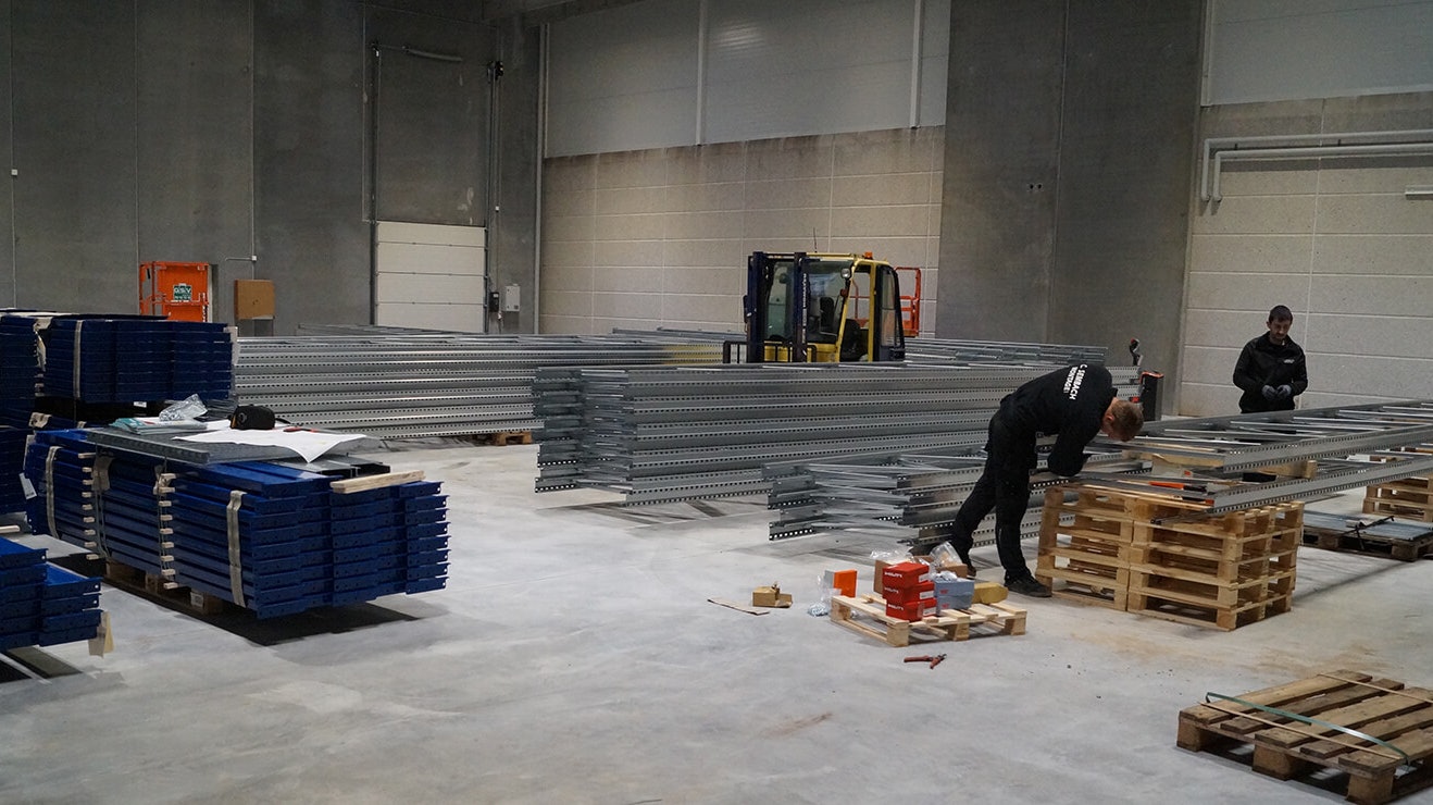 Drei Monteure beim Aufbau von Palettenregalen