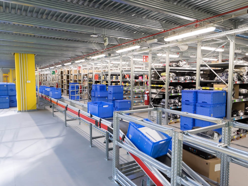 BITO Eurostapelbehälter auf einem Förderband, im Hintergrund Fachbodenregale