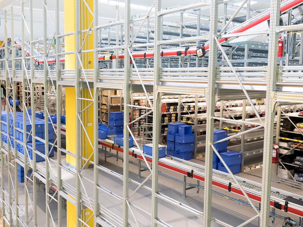 BITO Eurostapelbehälter vor und auf einer Rollenbahn, im Hintergrund stehen Fachbodenregale