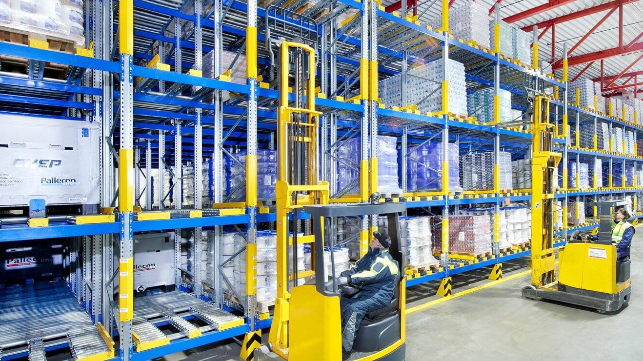 Zwei Arbeiter auf Flurförderzeugen an einem Palettendurchlaufregal