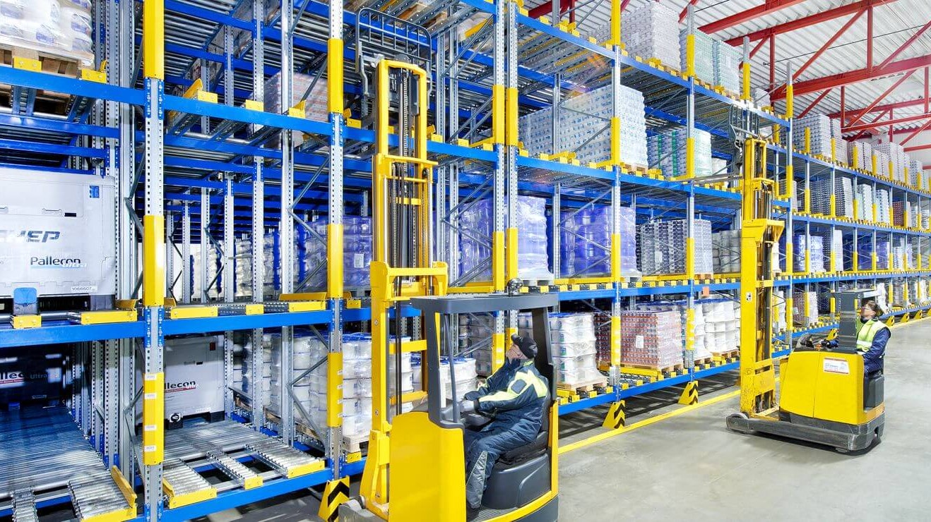 Zwei Arbeiter auf Flurförderzeugen an einem Palettendurchlaufregal