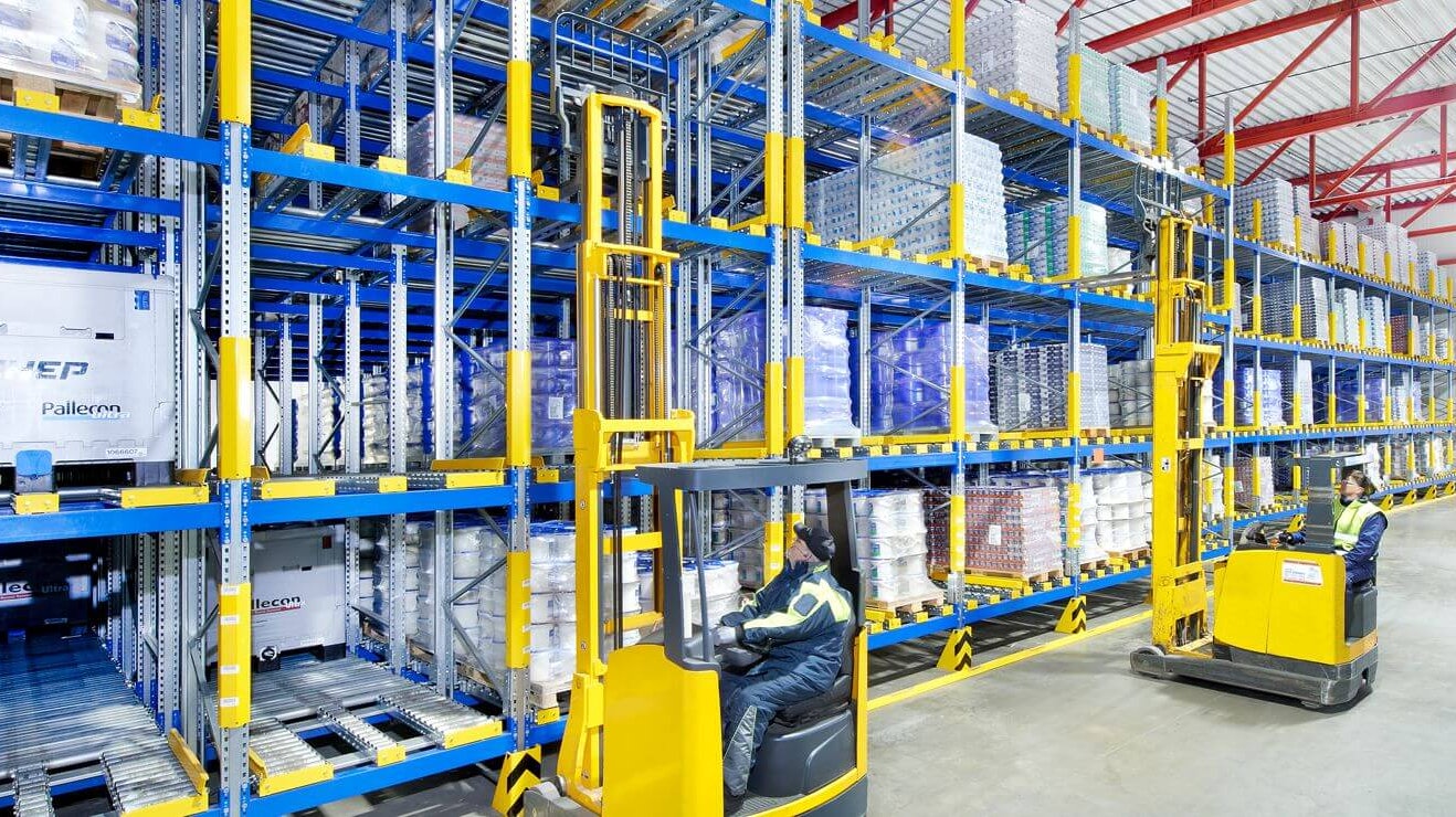 Zwei Arbeiter auf Flurförderzeugen an einem Palettendurchlaufregal