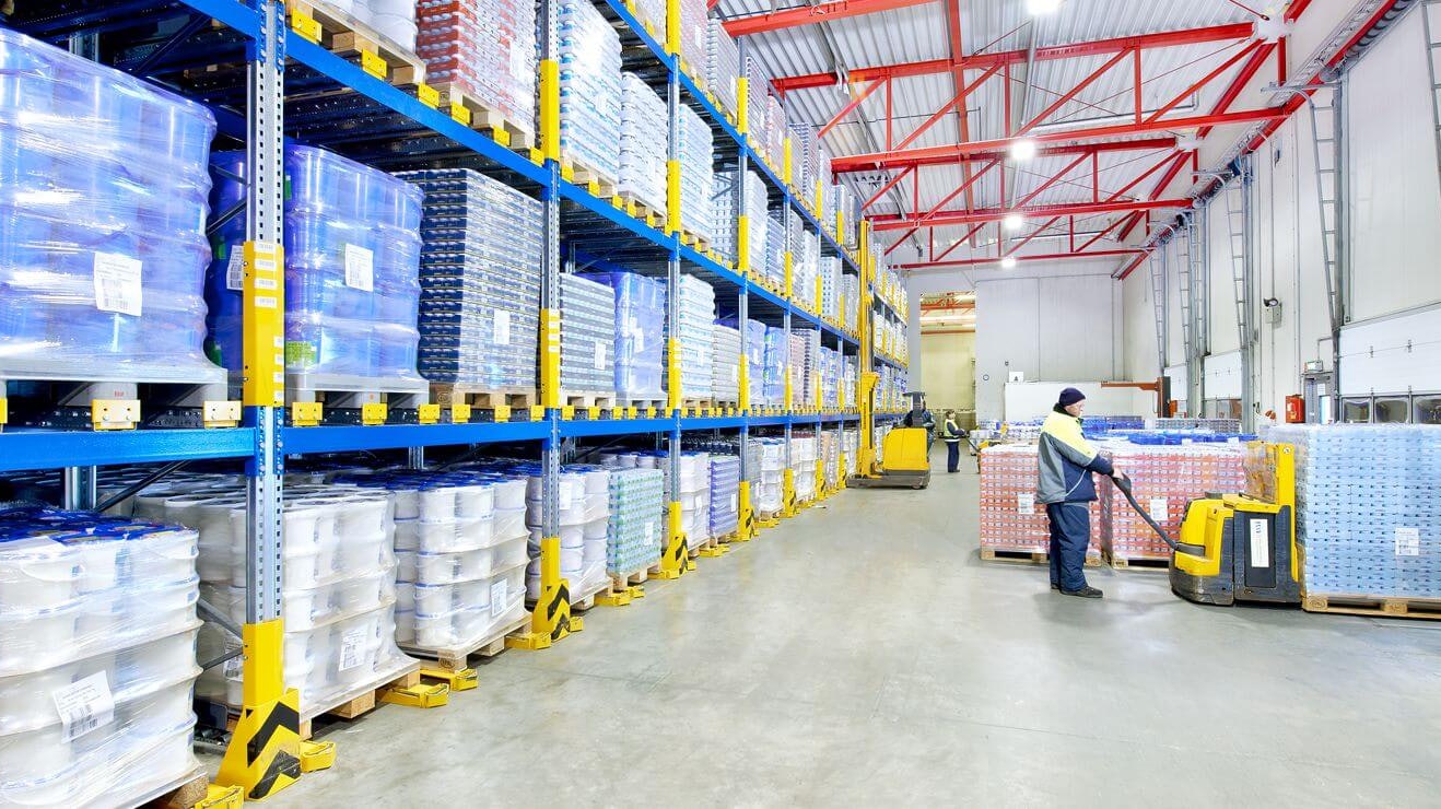 Drei Männer auf Flurförderzeugen an einem Palettendurchlaufregal