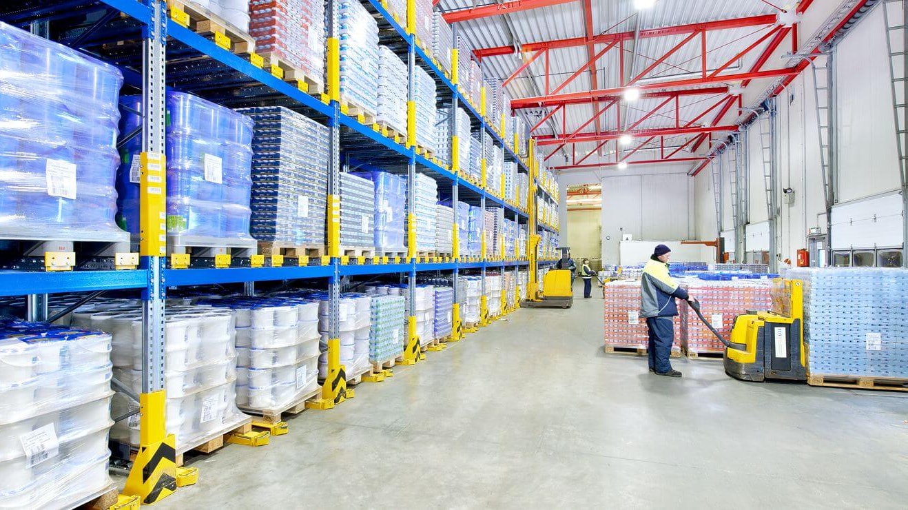 Drei Männer auf Flurförderzeugen an einem Palettendurchlaufregal