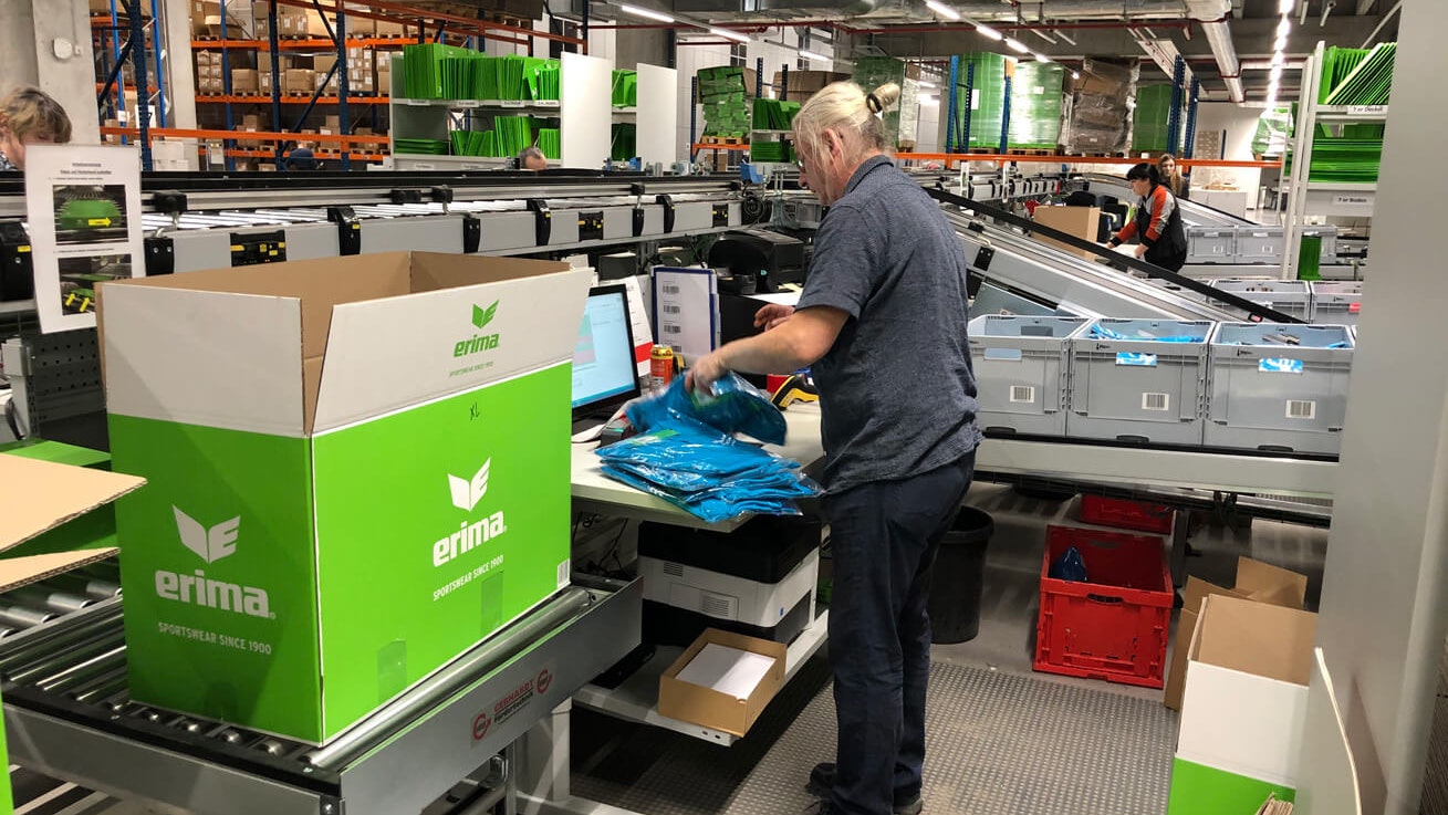 Mitarbeiter entnehmen Waren aus BITO Behältern und verpacken sie