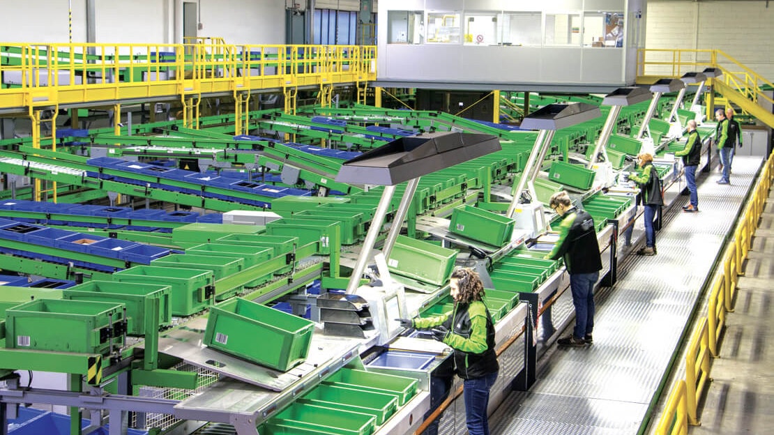 Mitarbeiter an einer Fördertechnik beim befüllen von BITO Behältern