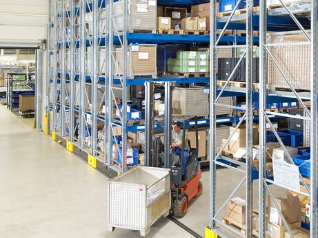 Ein Mitarbeiter auf einem Flurförderzeug in einem Platzsparendem Verfahrbaren Palettenregal von BITO