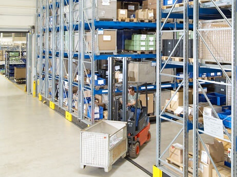 Ein Mitarbeiter auf einem Flurförderzeug in einem Platzsparendem Verfahrbaren Palettenregal von BITO