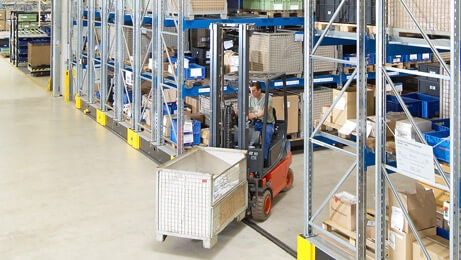 Ein Mitarbeiter auf einem Flurförderzeug in einem Platzsparendem Verfahrbaren Palettenregal von BITO