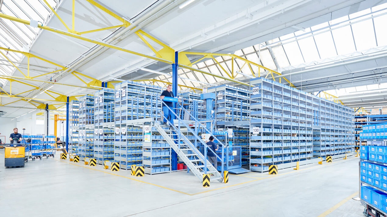 Mitarbeiter an einer Mehrgeschossanlage mit Fachbodenregalen