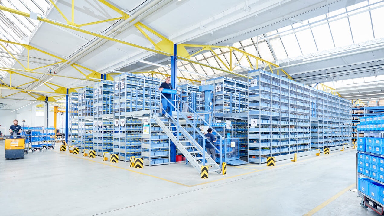 Mitarbeiter an einer Mehrgeschossanlage mit Fachbodenregalen