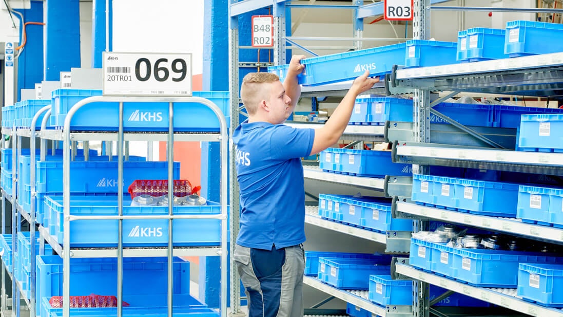 Ein Mitarbeiter mit Regalwagen vor einem BITO Durchlaufregal mit BITO Behältern