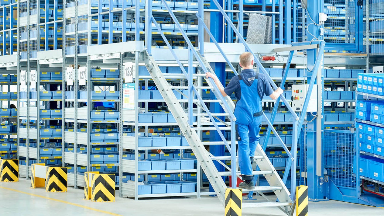 Mitarbeiter an einer Mehrgeschossanlage mit Fachbodenregalen